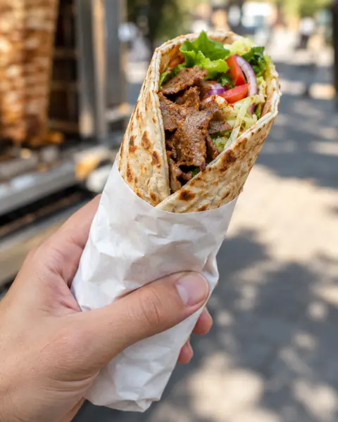 Dürüm mit Kalbfleisch und Salat, halb in Papier eingewickelt